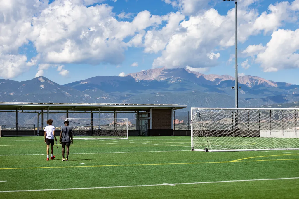 students walking on alpine field with mountains in the background